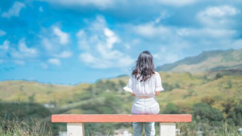 Girl Sitting on Bench Overlooking Scenic Mountain Landscape Desktop Wallpaper