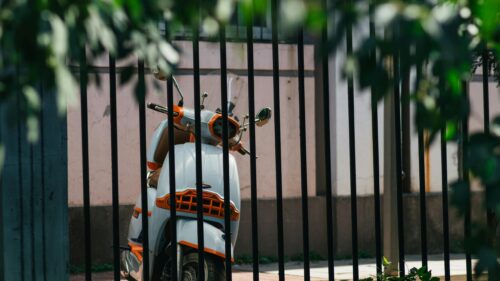 Vintage Style Scooter Behind Black Metal Fence Desktop Wallpaper
