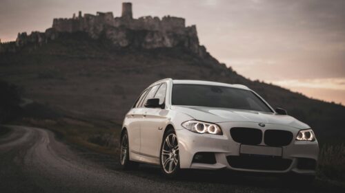 White BMW 5 Series Touring at Spiš Castle Sunset 4K Wallpaper