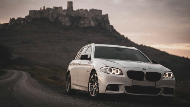White BMW 5 Series Touring at Spiš Castle Sunset 4K Wallpaper