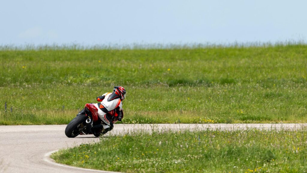 Professional Motorcycle Racer Cornering on Rural Road Desktop Wallpaper