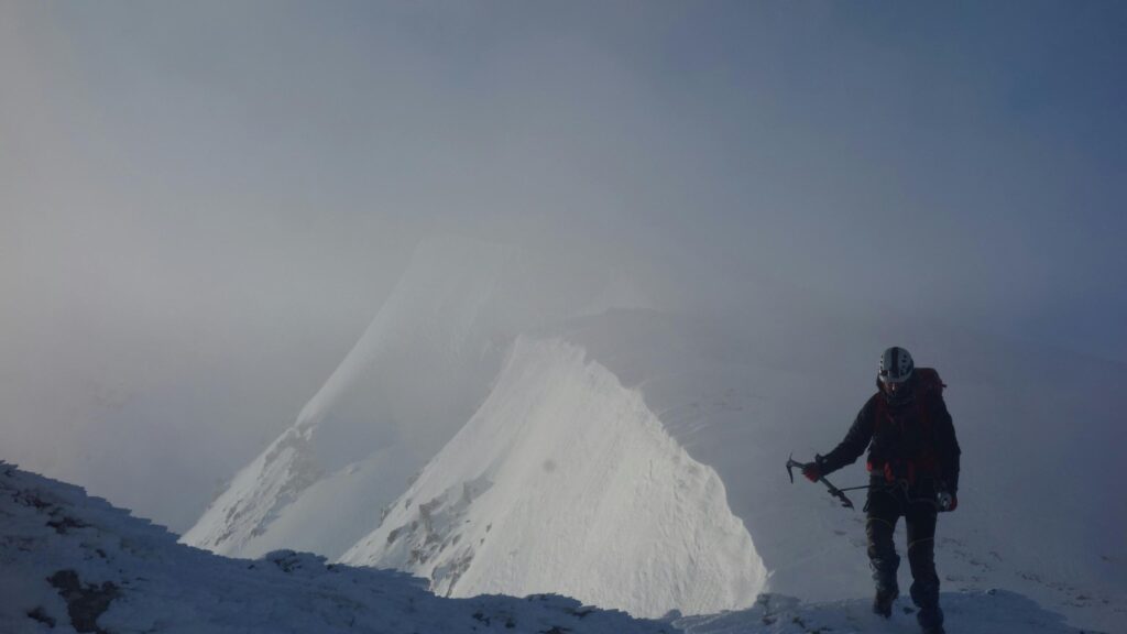 Solo Alpinist on Snowy Mountain Summit 4K Wallpaper