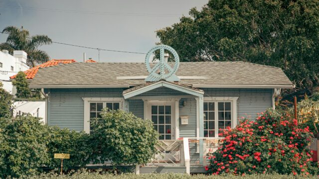 Charming Blue Cottage with Peace Sign Roof Decor 4K Desktop Wallpaper
