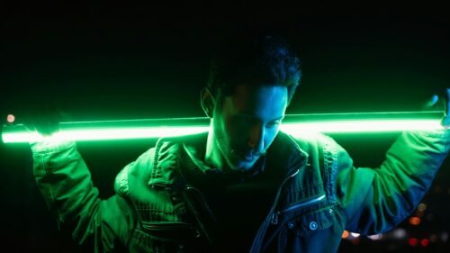 Man Holding Glowing Green Neon Light Stick Cinematic Portrait 4K Wallpaper