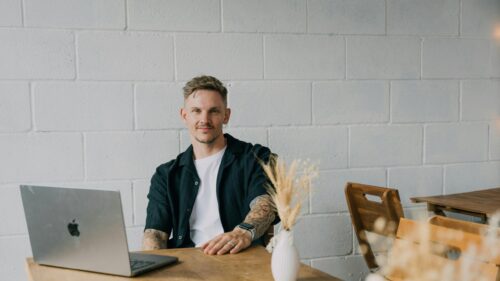 Young Man Working on Laptop in Modern Minimalist Cafe 4K Wallpaper