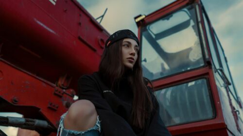 Stylish Girl Sitting by Red Industrial Machine Desktop Wallpaper