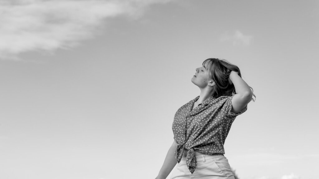 Dreamy Young Woman in Polka Dot Shirt Under Open Sky Desktop Wallpaper