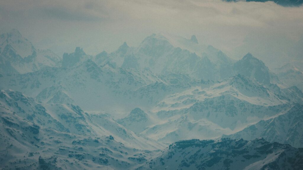 Majestic Snowy Peaks in Atmospheric Mist 4K Desktop Wallpaper