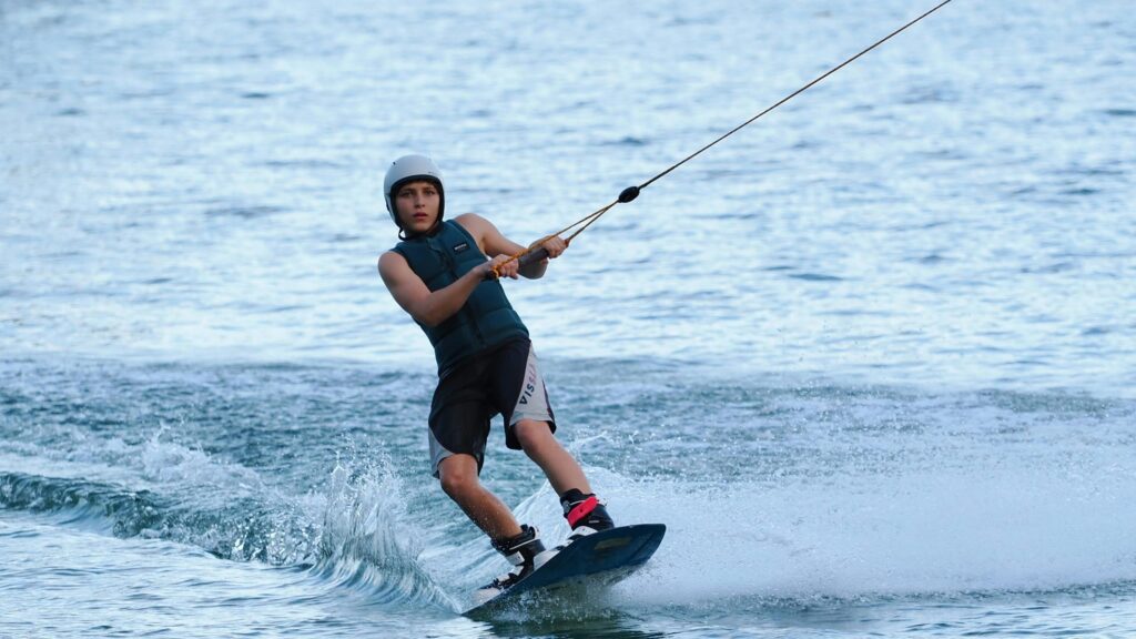 Young Wakeboarder Riding Waves on Blue Water Desktop Wallpaper