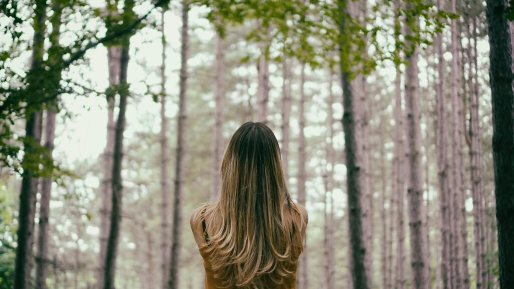 Back View of Woman with Long Blonde Hair Standing in Forest Desktop Wallpaper