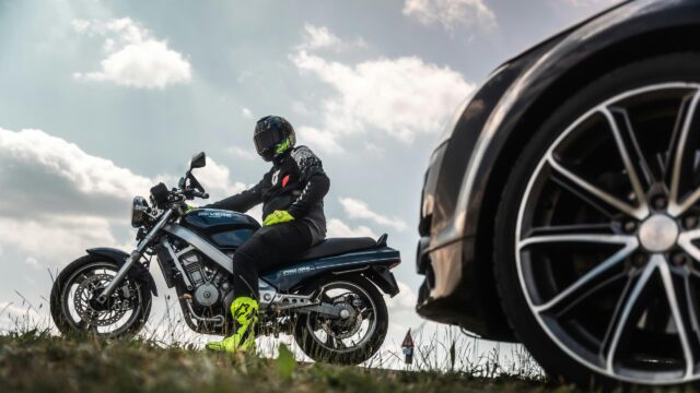 Motorcyclist Riding Honda Revere Next to Luxury Car 4K Wallpaper