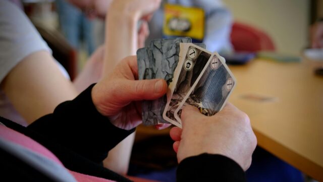 Close-up of a Person Holding Strategy Board Game Cards Desktop Wallpaper