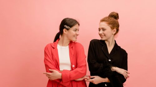 Two Fashionable Women Smiling in Red and Black Outfits 4K Desktop Wallpaper
