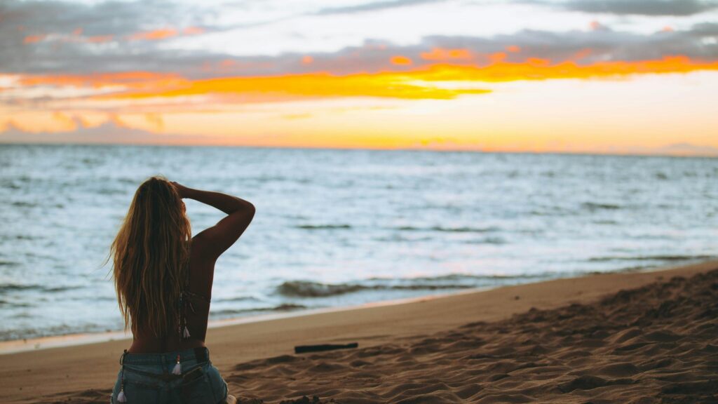 Woman Sitting on Beach at Sunset 4K Desktop Wallpaper