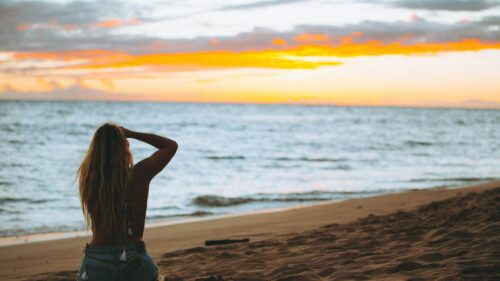 Woman Sitting on Beach at Sunset 4K Desktop Wallpaper