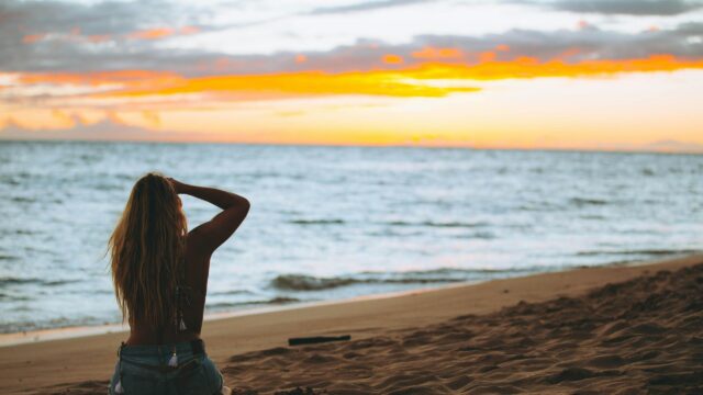 Woman Sitting on Beach at Sunset 4K Desktop Wallpaper