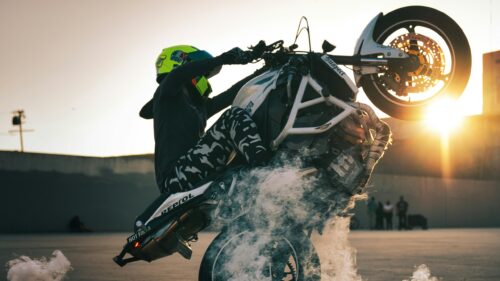 Stunt Rider Performing Intense Motorcycle Wheelie at Sunset 4K Wallpaper