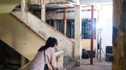 Woman Standing in Dilapidated Urban Interior with Soft Lighting 4K Wallpaper