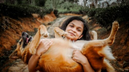 Happy Girl Holding Her Playful Dog in Scenic Nature Desktop Wallpaper