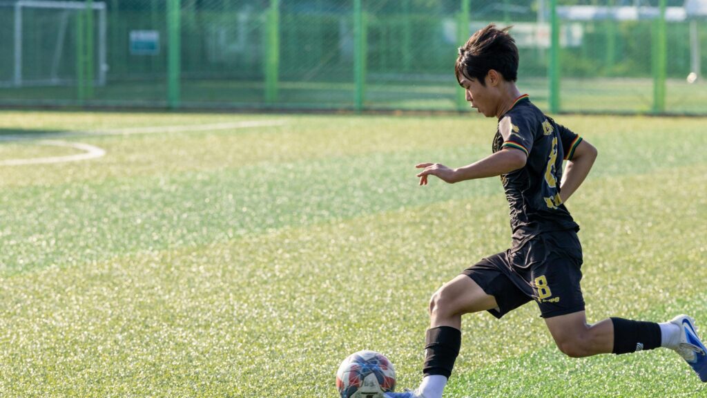 Young Soccer Player Dribbling on Grass Field Desktop Wallpaper