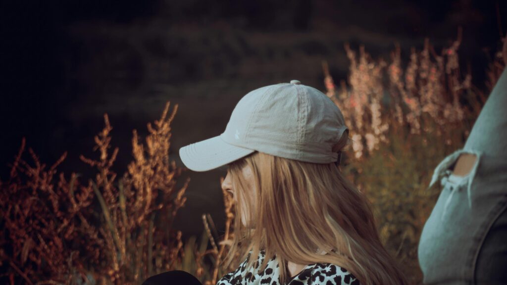 Blonde Girl in Baseball Cap Sitting in Golden Sunset 4K Wallpaper
