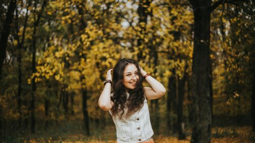Happy Woman with Long Curly Hair in Autumn Forest Desktop Wallpaper