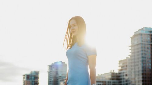Sun-Kissed Woman in Blue Dress Against Urban Skyline PC Wallpaper