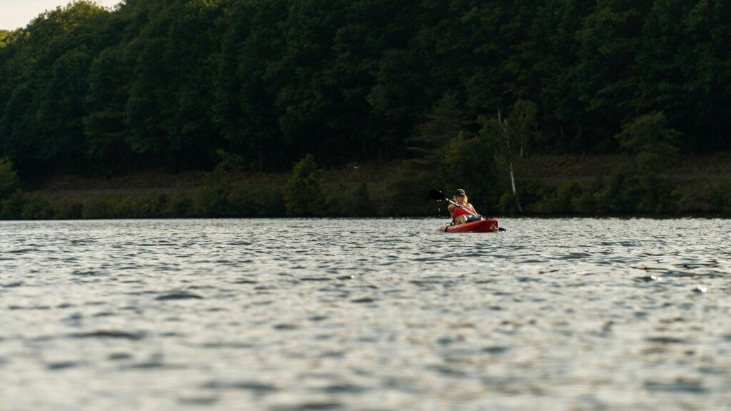 Serene Woman Kayaking on Calm Lake at Sunset 4K Desktop Wallpaper