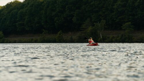 Serene Woman Kayaking on Calm Lake at Sunset 4K Desktop Wallpaper