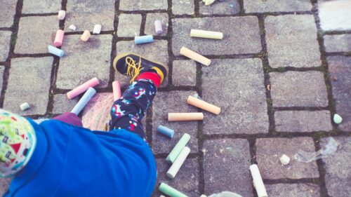 Child Playing with Colorful Sidewalk Chalk on Stone Pavement Desktop Wallpaper
