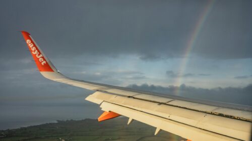 EasyJet Airplane Wing with Rainbow Over Scenic Landscape 4K Wallpaper