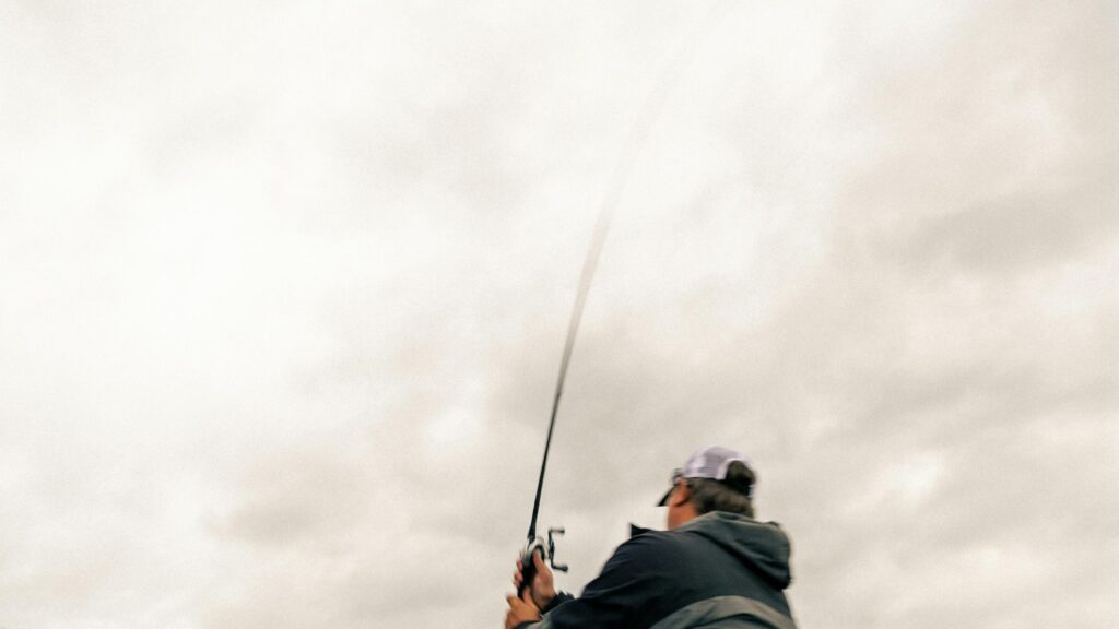 Fisherman Casting Fishing Rod Against Cloudy Sky 4K Desktop Wallpaper