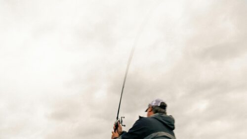 Fisherman Casting Fishing Rod Against Cloudy Sky 4K Desktop Wallpaper