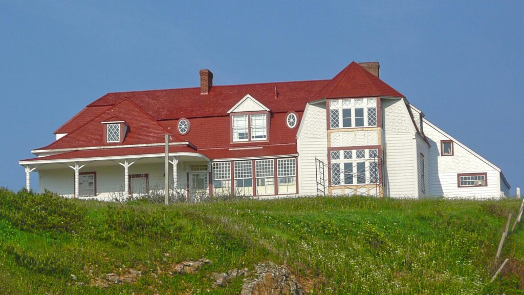 Charming Country House with Red Roof on Grassy Hillside Desktop Wallpaper