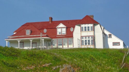 Charming Country House with Red Roof on Grassy Hillside Desktop Wallpaper