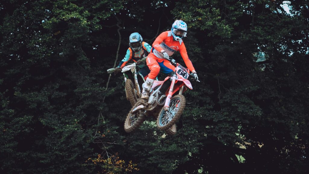 Two Motocross Riders Jumping Mid-Air Action PC Wallpaper