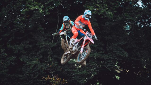 Two Motocross Riders Jumping Mid-Air Action PC Wallpaper