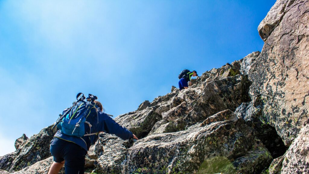 Adventurous Hikers Climbing Rocky Mountain Peak Desktop Wallpaper