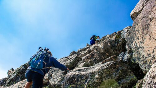 Adventurous Hikers Climbing Rocky Mountain Peak Desktop Wallpaper