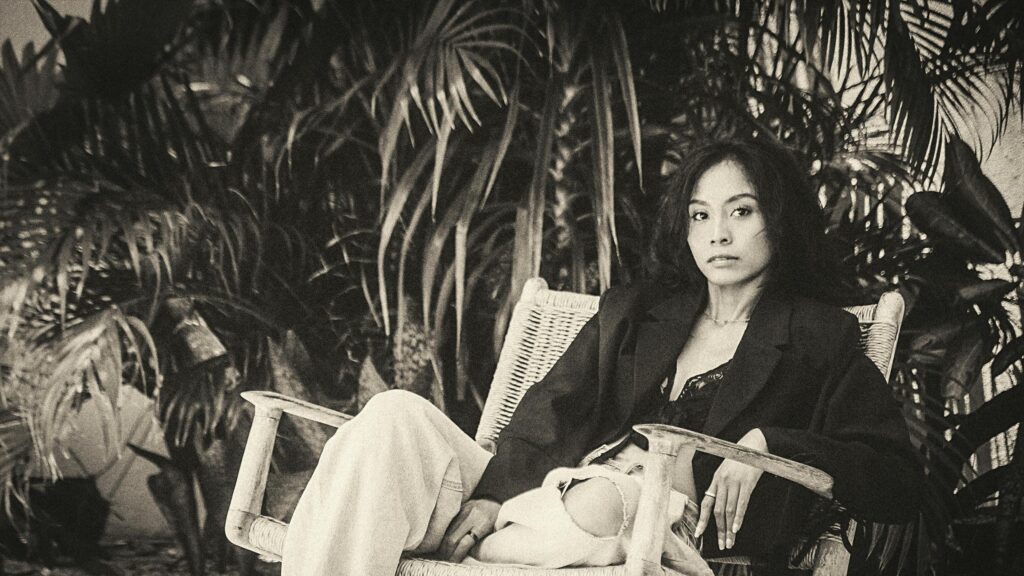 Elegant Woman in Black Blazer Relaxing in Tropical Garden Desktop Wallpaper