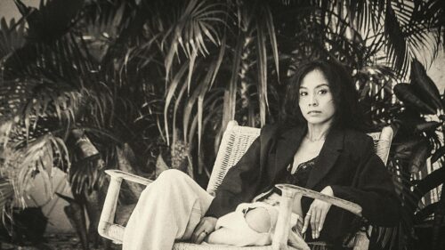 Elegant Woman in Black Blazer Relaxing in Tropical Garden Desktop Wallpaper