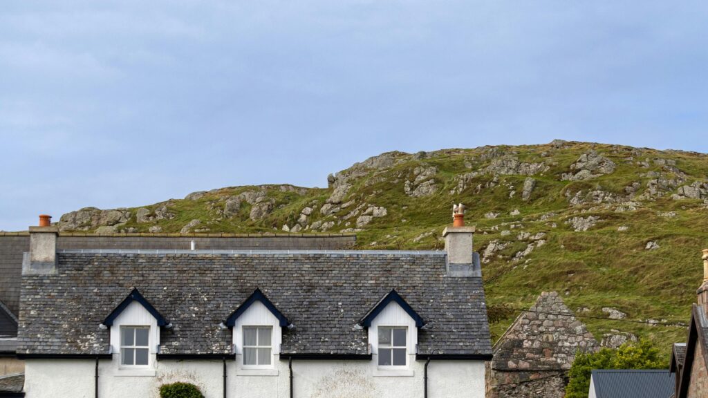 Quaint Cottage Under Rocky Highland Hills Desktop Wallpaper