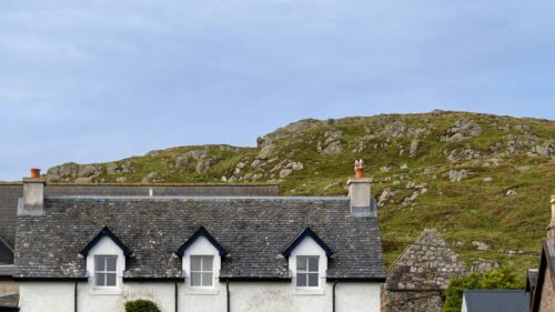 Quaint Cottage Under Rocky Highland Hills Desktop Wallpaper