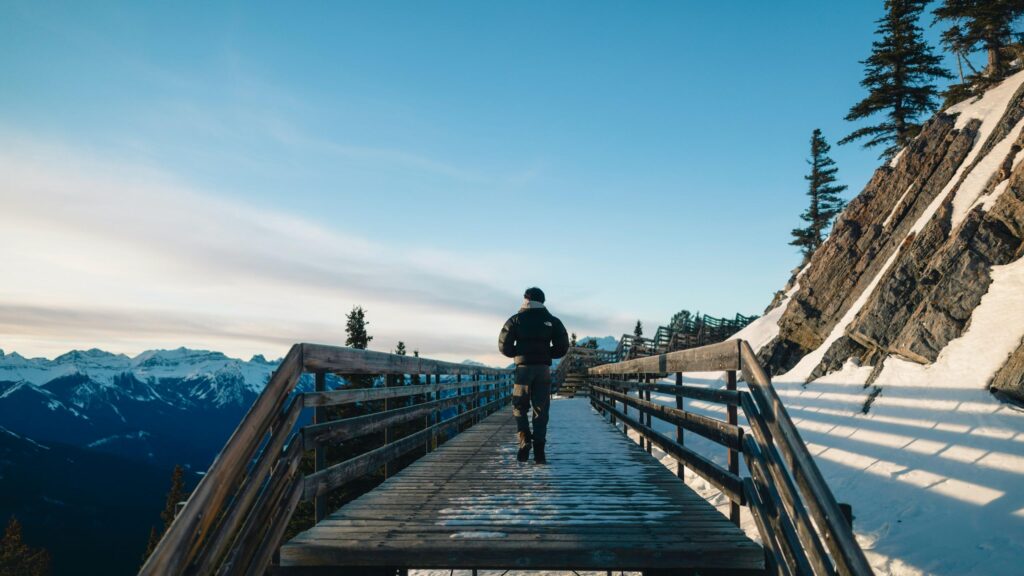 Hiker Walking on Snowy Mountain Boardwalk 4K Desktop Wallpaper