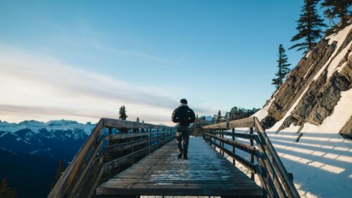 Hiker Walking on Snowy Mountain Boardwalk 4K Desktop Wallpaper