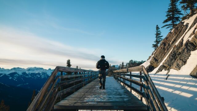 Hiker Walking on Snowy Mountain Boardwalk 4K Desktop Wallpaper
