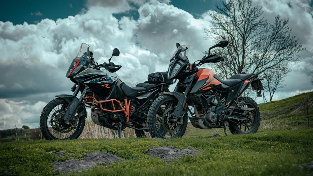 Two KTM Adventure Motorcycles Parked in a Grassy Field 4K Wallpaper