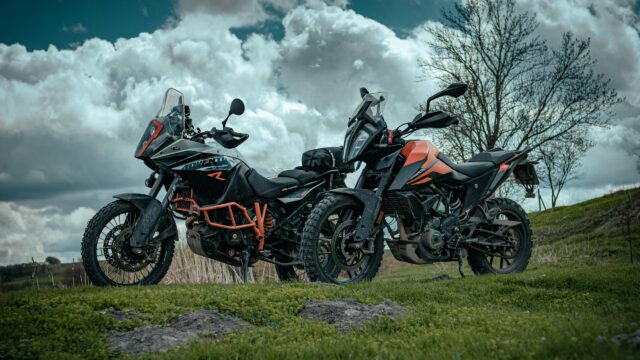 Two KTM Adventure Motorcycles Parked in a Grassy Field 4K Wallpaper