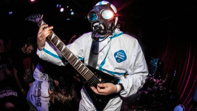 Musician in Hazmat Suit Performing Heavy Metal Concert 4K Wallpaper