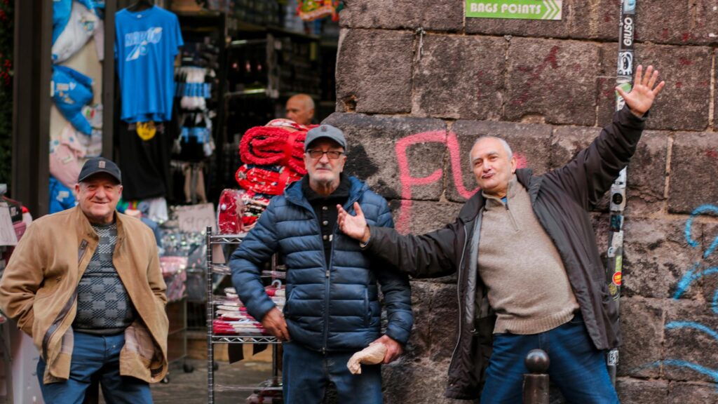 Three Cheerful Italian Men Standing on a Charming Street Desktop Wallpaper